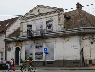 Sepsiszentgyörgyi lány arca az egykori, romosodó Csacsa bár homlokzatán. A szerző felvétele