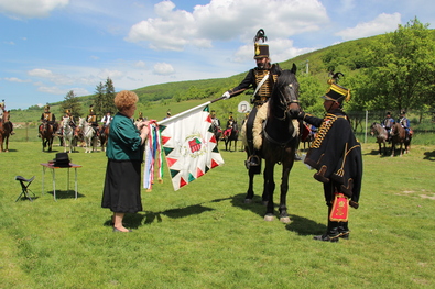  Huszártoborzó Málnáson – Szotyori Angéla polgármester feltűzi a díszzászlóra a község szalagját. Fotó: Hecser László