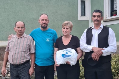 Gáspár Jenő bodosi falufelelős (balról), Demeter Zoltán és Iszlai Kamill Zsolt bodosi lelkipásztor átadja az adományt a tűzkárosult Virág Lujzának. Fotó: Gondviselés Segélyszervezet
